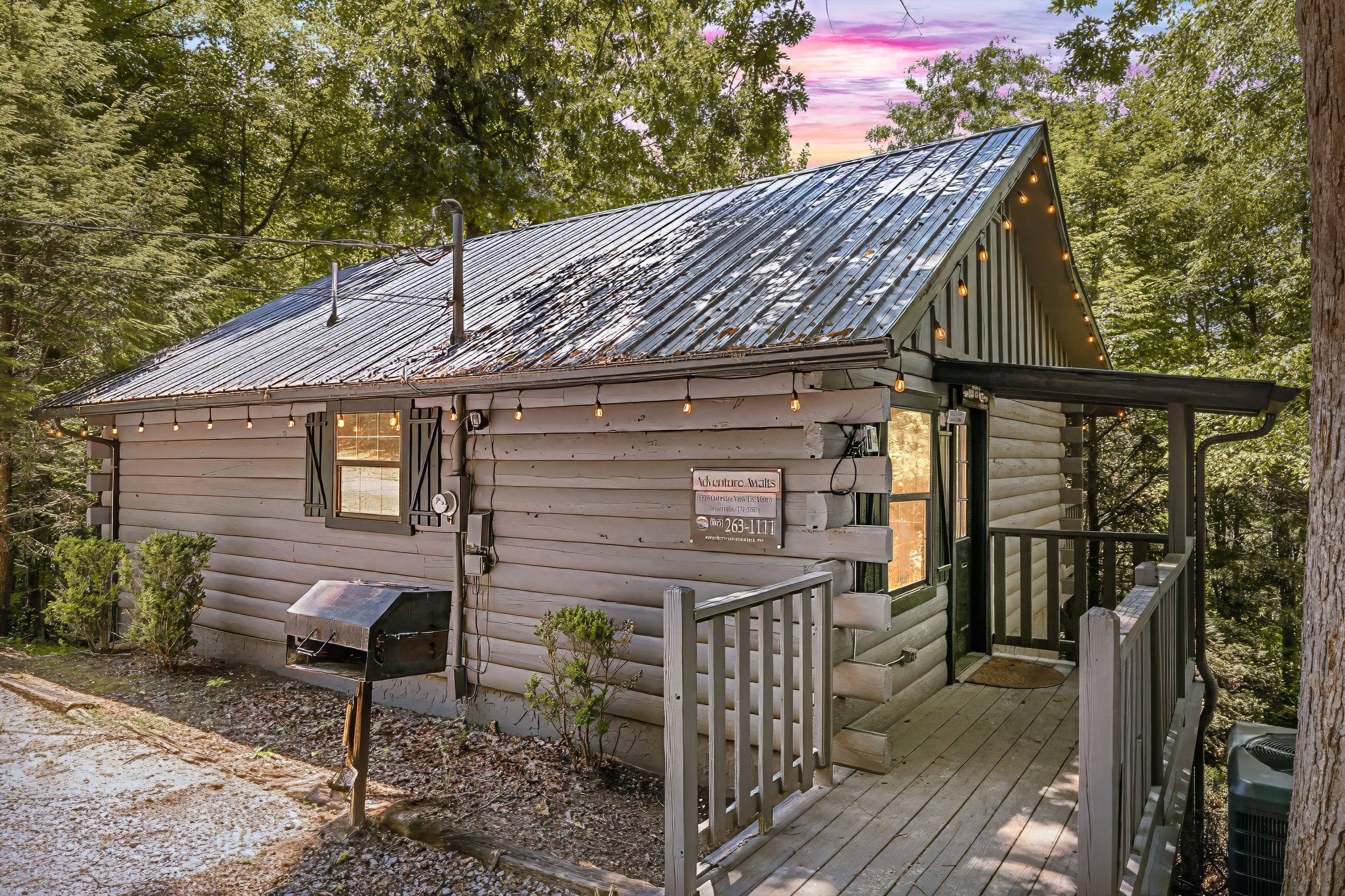 Exterior of Adventure Awaits cabin surrounded by trees at dusk